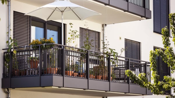 Balkon mit Pflanzen und Sonnenschirm an einem modernen Mehrfamilienhaus