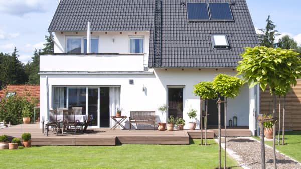 Weißes freistehendes Einfamilienhaus mit Terrasse im Grünen