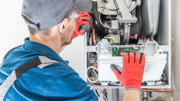 Handwerker in Arbeitskleidung arbeitet an einer Gastherme