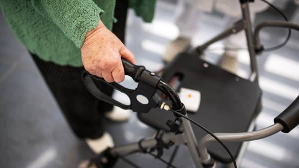 Seniorin in schwarzer Hose und grünem Oberteil mit einem Rollator