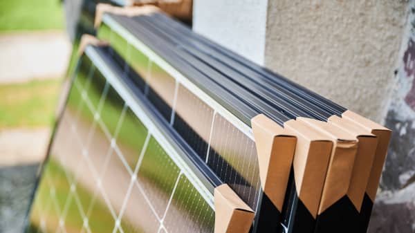 Mehrere verpackte Solarmodule lehnen am Äußeren eines Gebäudes