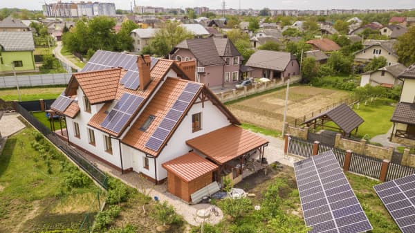 Wohnhäuser im Grünen mit Dach-Solaranlagen und freistehenden Solarmodulen