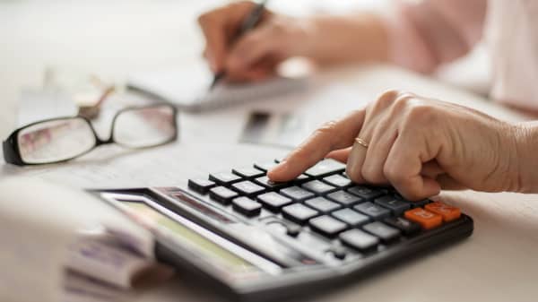 Nahaufnahme der Hände einer älteren Frau, die auf einem Taschenrechner tippt