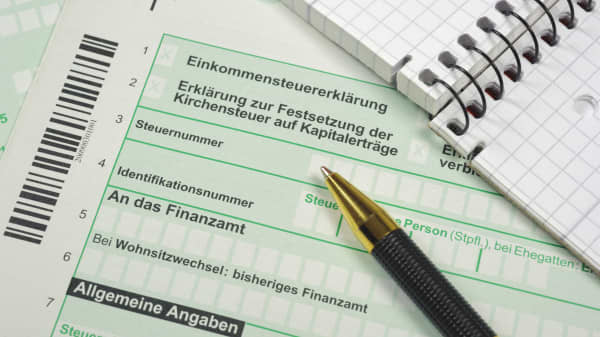 Formulare zur Einkommensteuererklärung mit Notizblock und Kugelschreiber