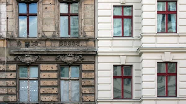 Frontansicht zweier Mehrfamilienhäuser, von denen das linke stark sanierungsbedürftig und das rechte bereits saniert ist