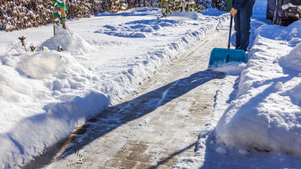 Verschneite Einfahrt, die von einer Person geräumt wird