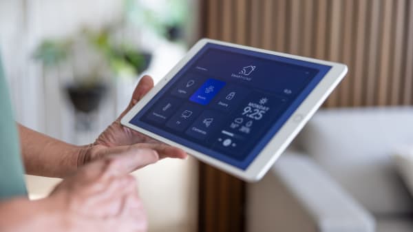 Ältere Person hält ein Tablet mit Smart-Home-Anwendung