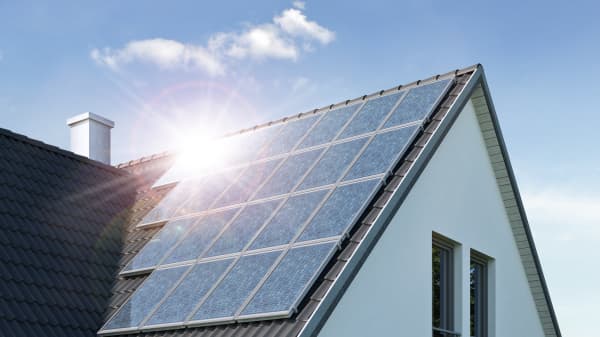 Sonne spiegelt sich in Solarmodulen auf dem Dach eines Wohnhauses