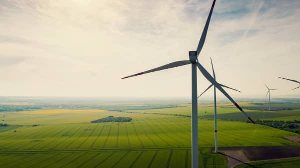 Windkraftanlagen auf grüner Wiese vor bewölktem Himmel