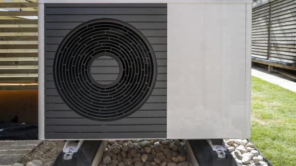 Luft-Wärmepumpe im Garten vor Holzwand zum Lärmschutz