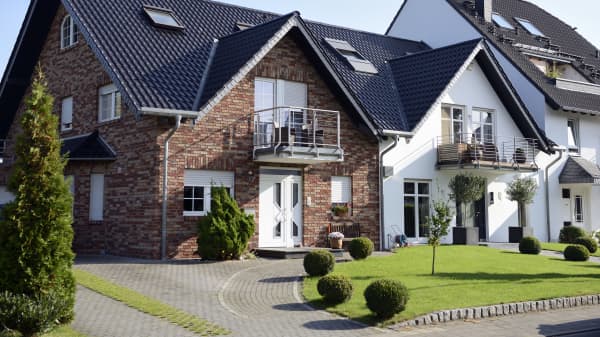 Modernisierte Einfamilienhäuser in Reihe gebaut mit gepflasterter Einfahrt und gepflegtem Rasen