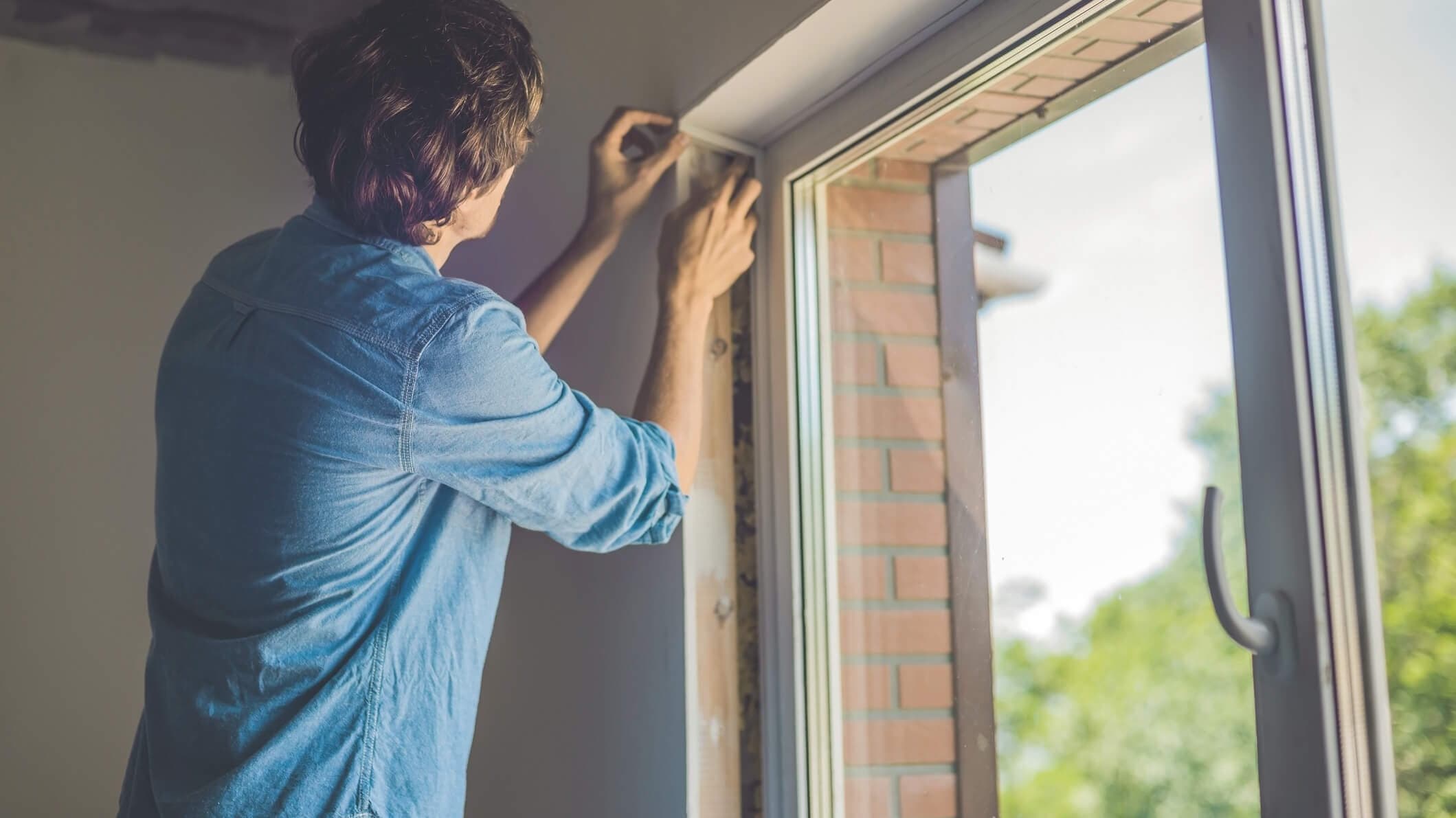 Mann baut neue Fenster in die Wohnung ein