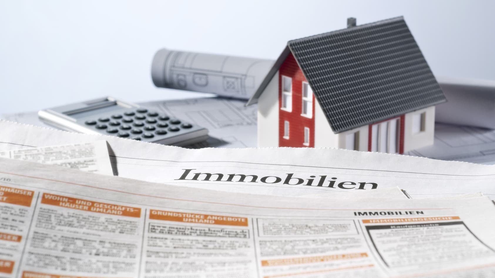 Baupläne, Taschenrechner, Modellhaus und Zeitungsinserate für Immobilien