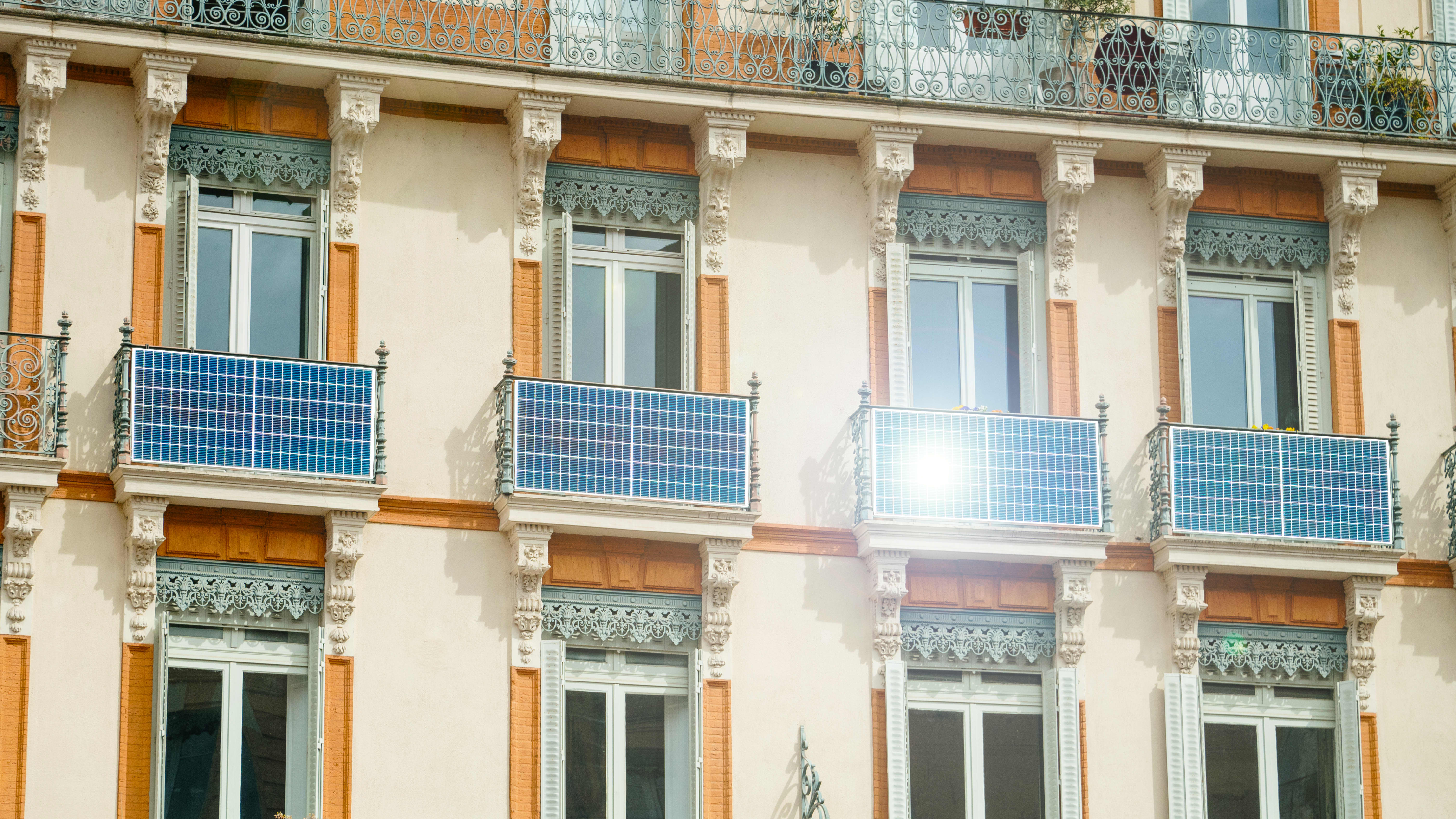 Fassade eines sanierten Altbaus mit Solarmodulen an mehreren Balkonen