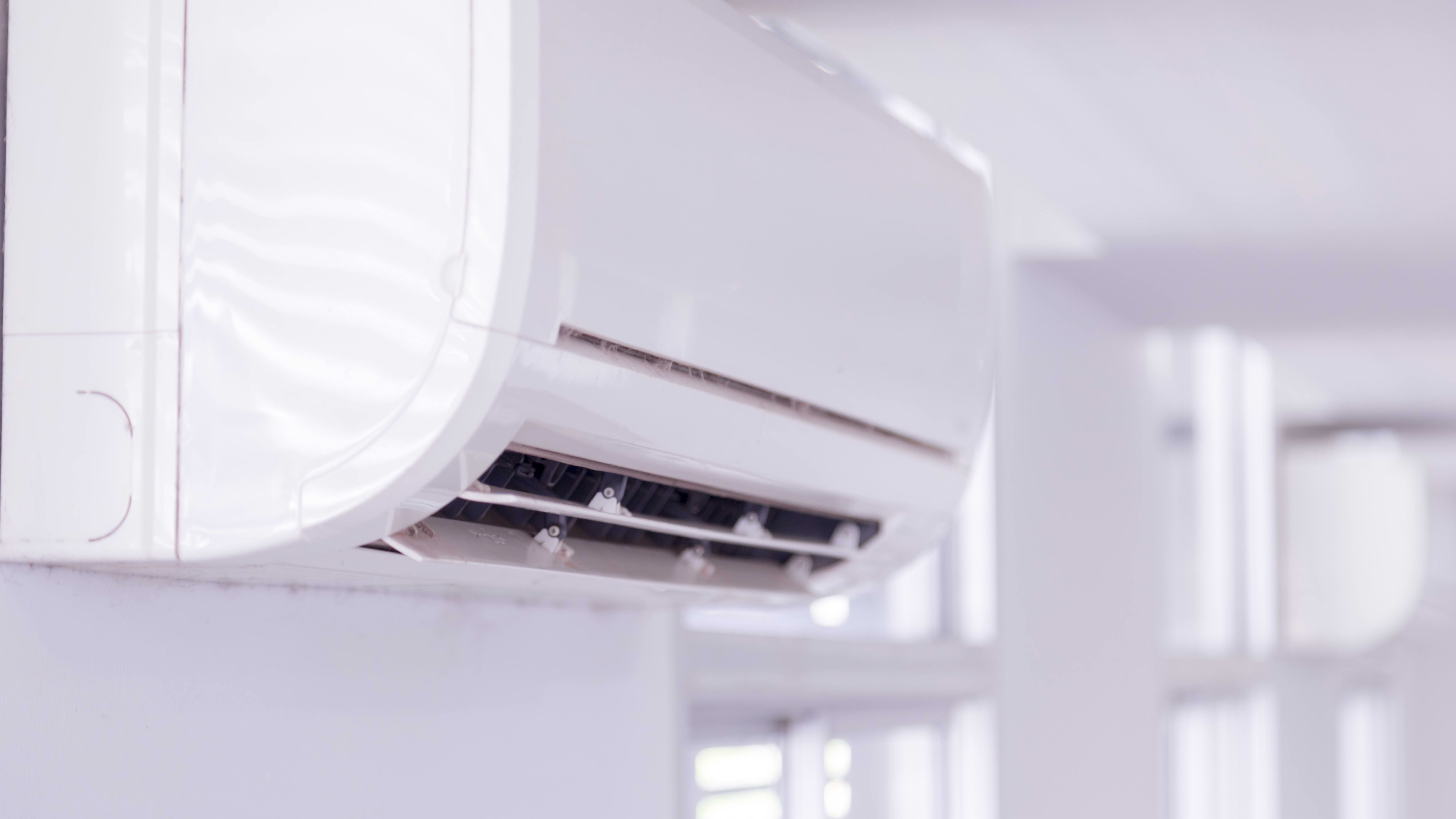 Nahansicht des Innengeräts einer fest installierten Klimaanlage in einem Raum mit weißen Wänden