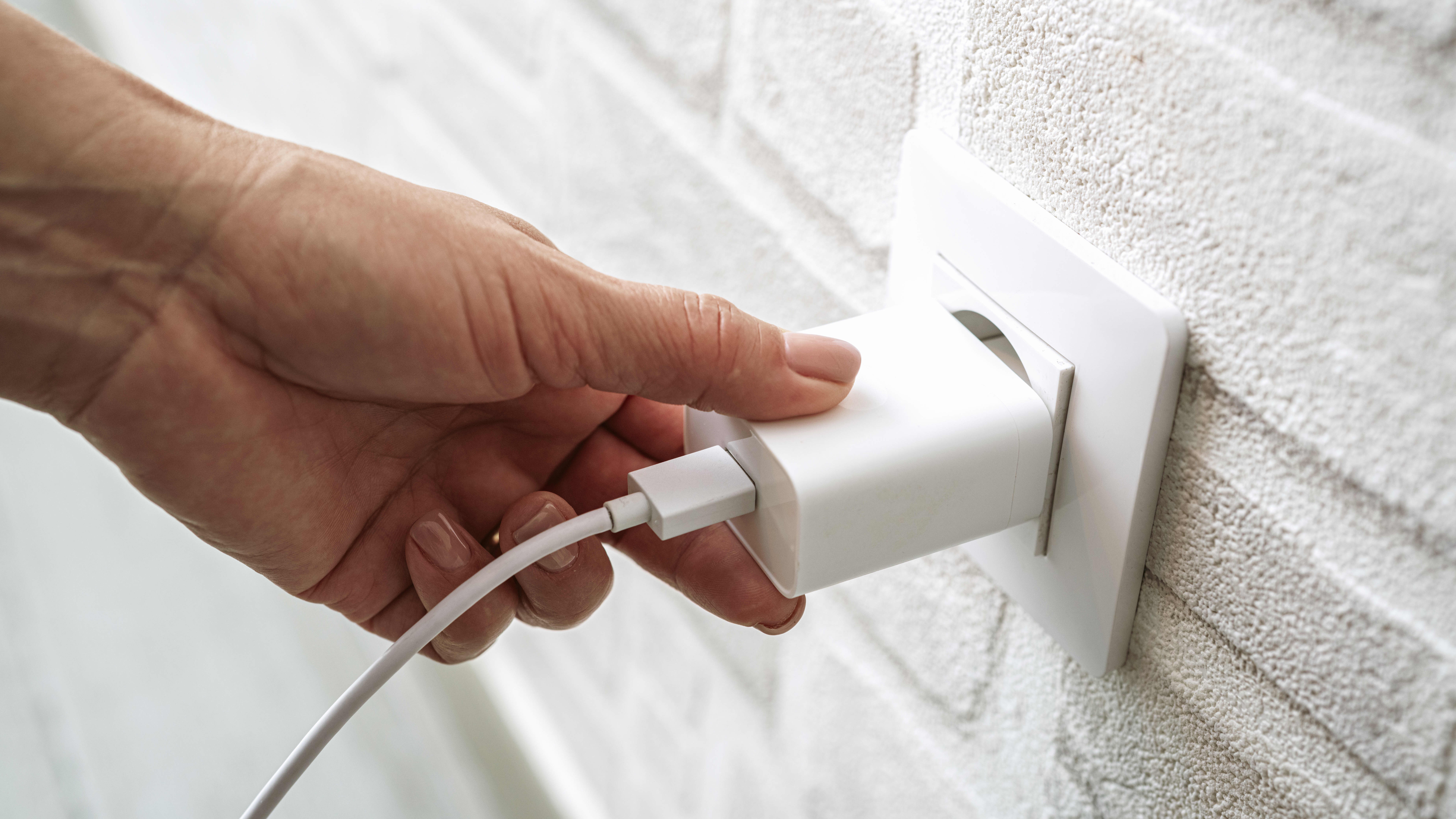 Nahaufnahme der Hand einer Person, die einen Stecker in eine Steckdose steckt
