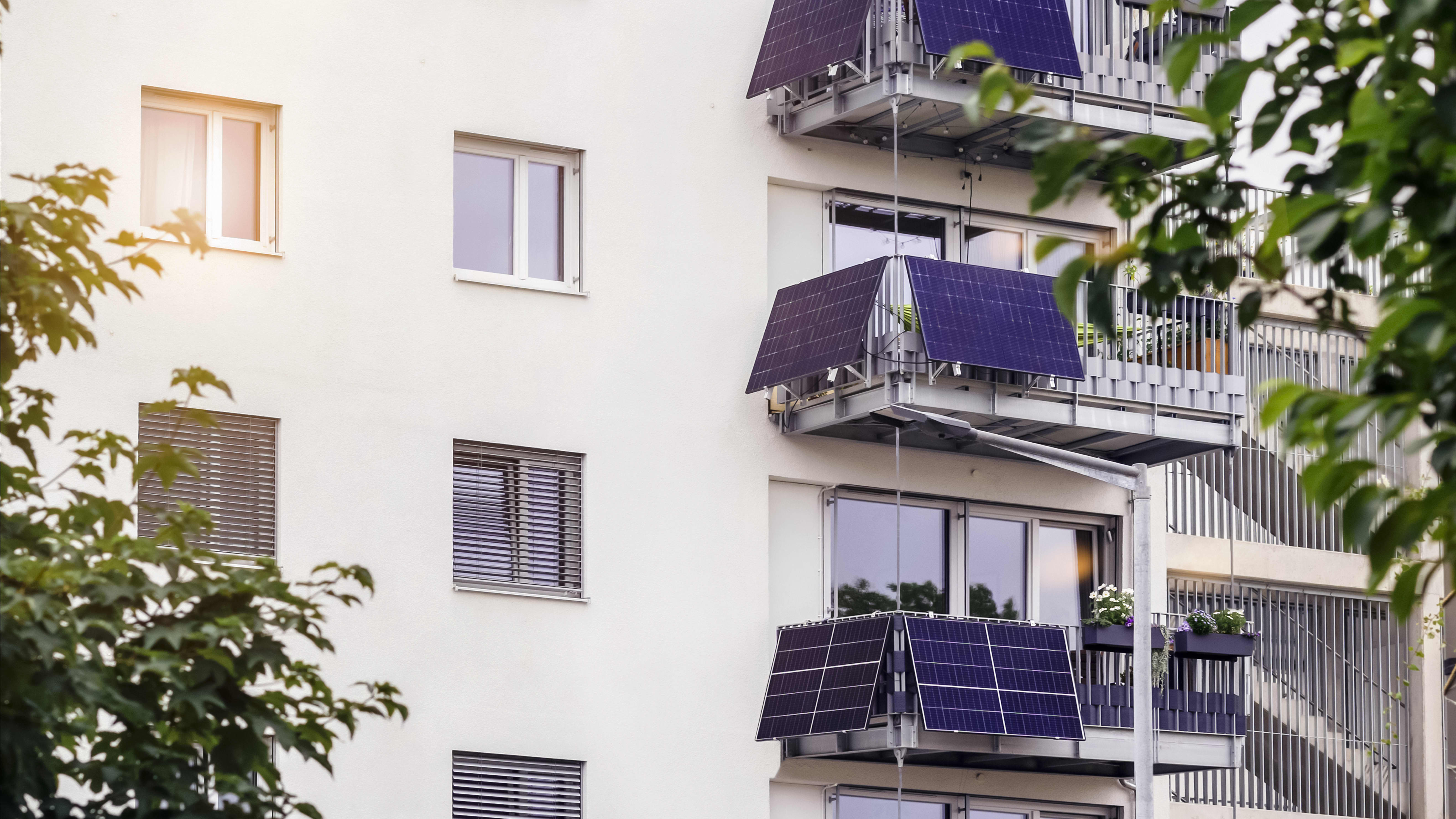 Ansicht der Fassade eines gepflegten Mehrfamilienhauses mit Balkonen, an denen sich Balkon-Solaranlagen befinden