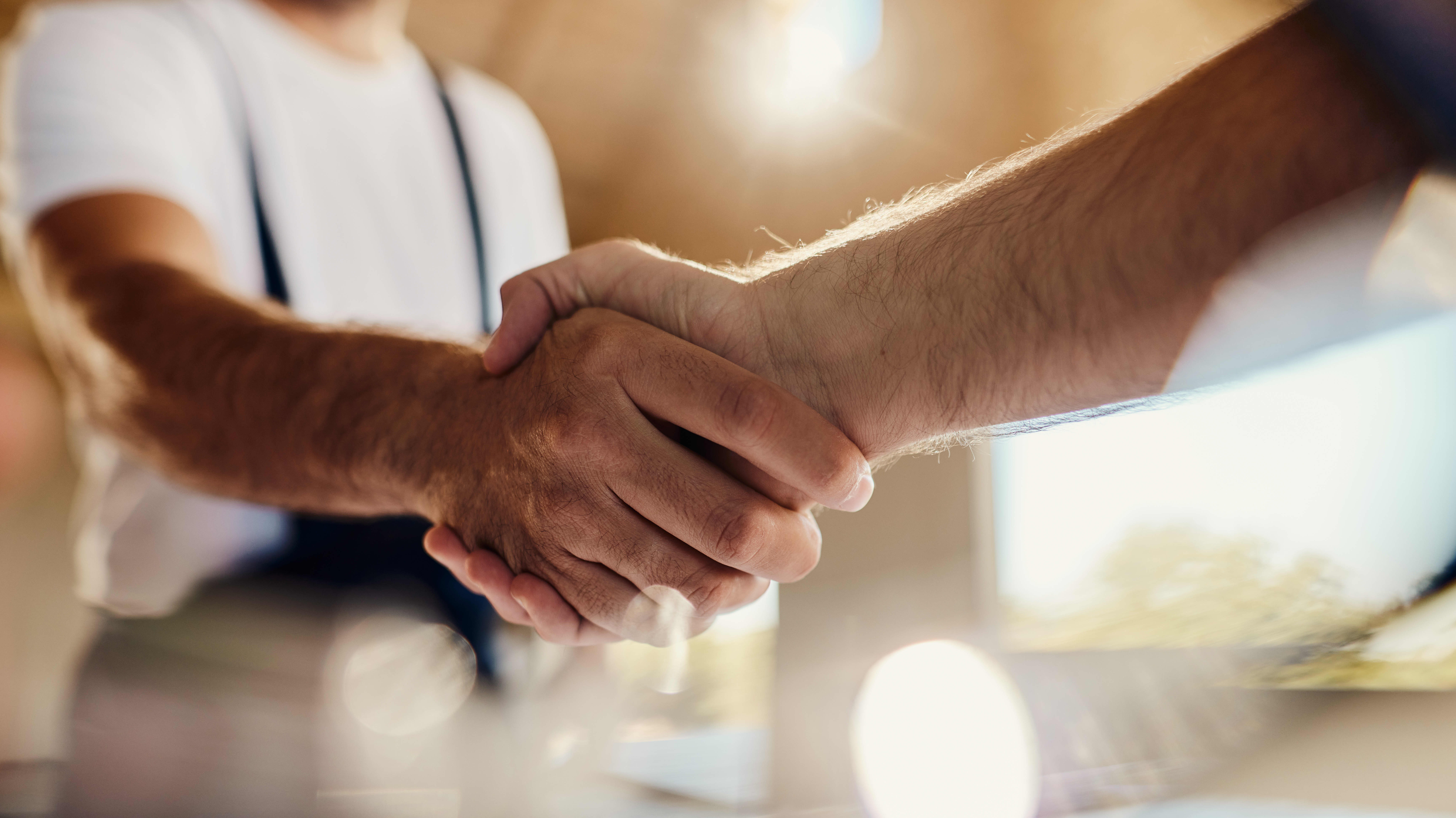 Nahaufnahme zweier Männer, die sich die Hand geben
