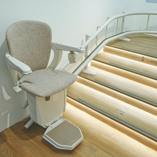 Sitzlift vor einer gewundenen und beleuchteten Treppe.