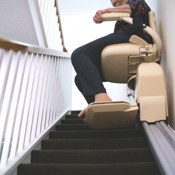 Blick eine Treppe hinauf auf eine Person in einem Treppenlift