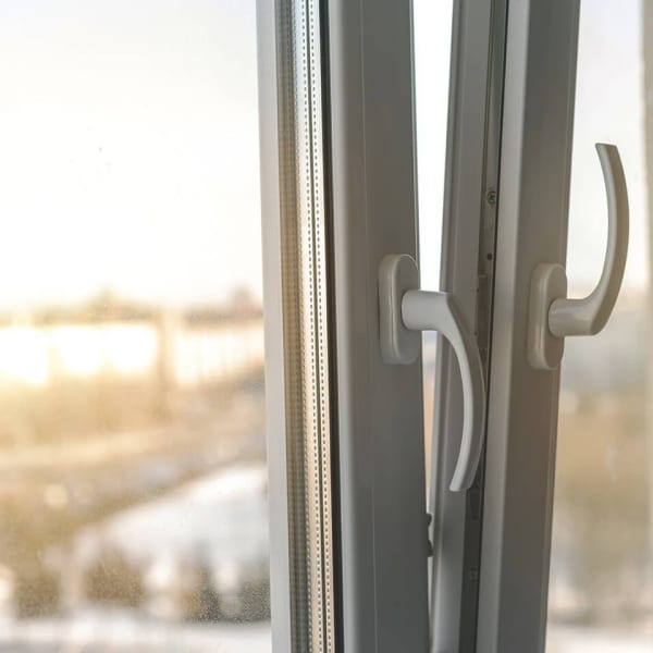 Geöffnetes Kunststoff-Fenster mit weißen Griffen bei Tageslicht