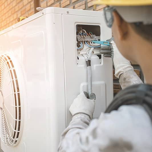 Installation einer Wärmepumpe an einer Hauswand.