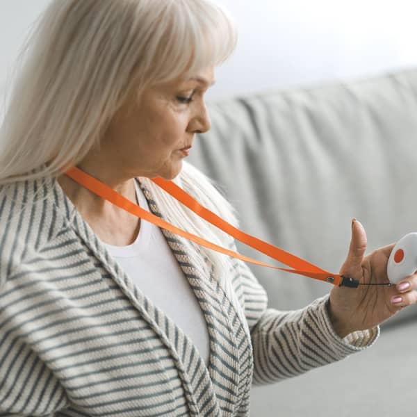 Frau betrachtet den Knopf für ihr Notrufsystem zu Hause