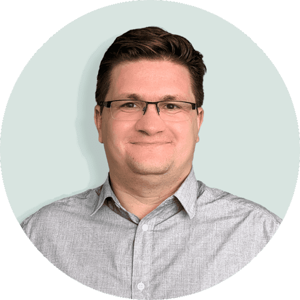 Das Bild zeigt ein Portrait von dem Energieexperten Alexander Steinfeldt. er hat kurze braune Haare, trägt eine Brille und ein graues Hemd.