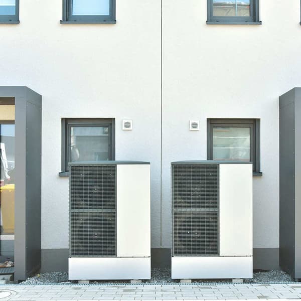 Zwei Wärmepumpen mit wenig Abstand vor einem Reihenhaus