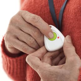 Der Knopf eines Hausnotrufs wird von einer älteren Person gedrückt.