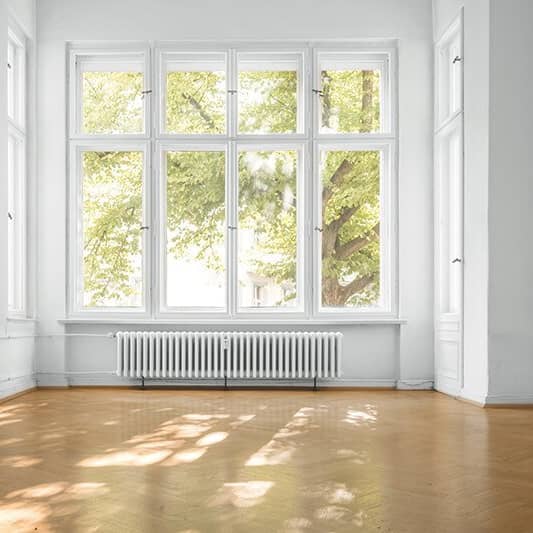 Heller Raum mit weißen Kastenfenstern, Heizkörper und Parkettboden