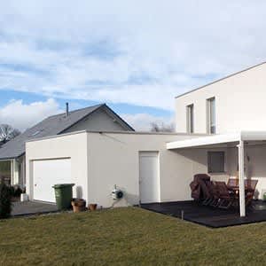 Weiße Garage mit Seitentür und Überdachung an ein Haus angebaut.