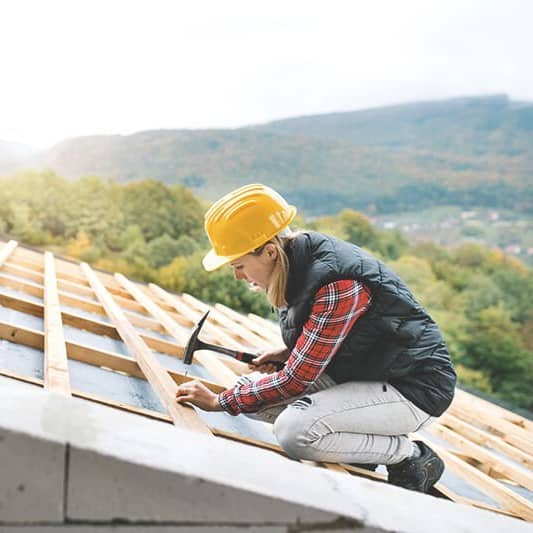 Dachdeckerin arbeitet auf einem Dachstuhl