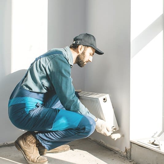 Heizungsbauer installiert einen Heizkörper im Haus