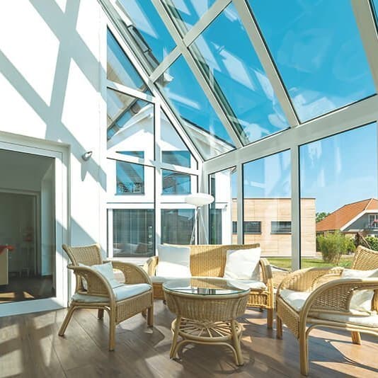 Moderner Wintergarten mit Glasdach und Rattanmöbeln