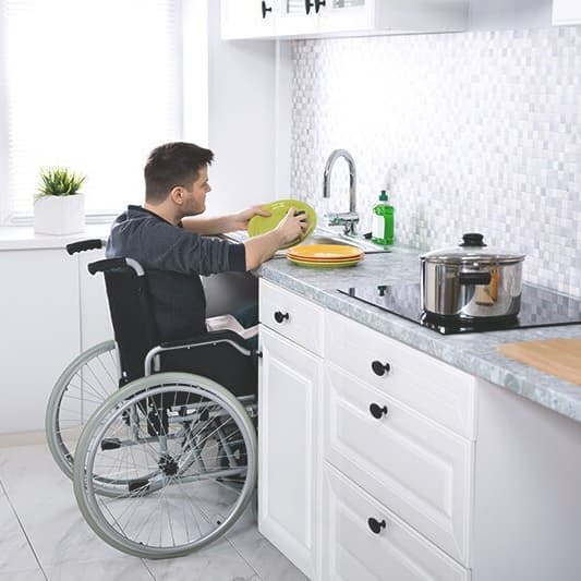 Rollstuhlfahrer an einer unterfahrbaren Spüle