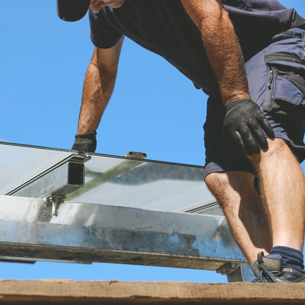 Handwerker montiert Terrassenüberdachung aus Glas