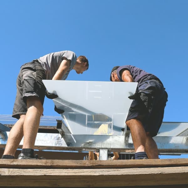 Zwei Handwerker installieren eine Glas-Terrassenüberdachung.