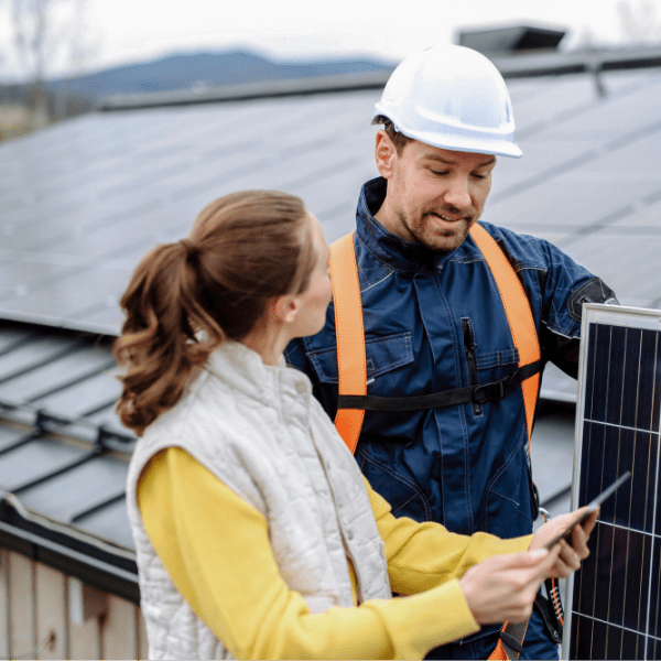 Hauseigentümerin lässt sich von einem Handwerker zum Thema Solaranlage vor einem Solardach beraten.