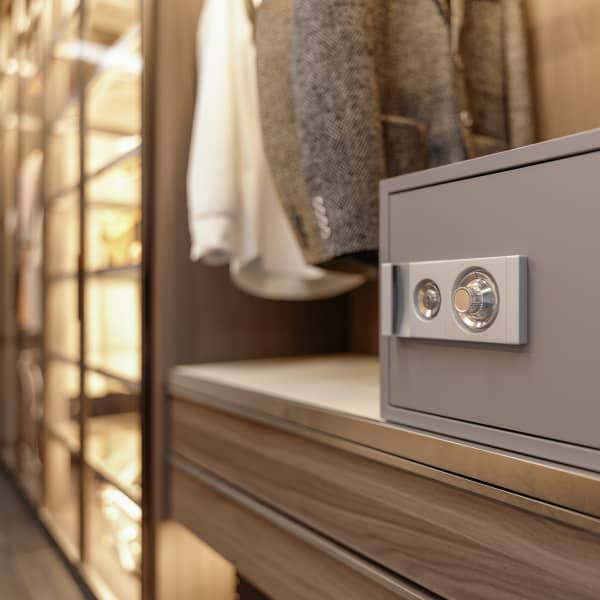 Gesperrter Banktresor im Kleiderschrank, daneben hängen zwei Jacken