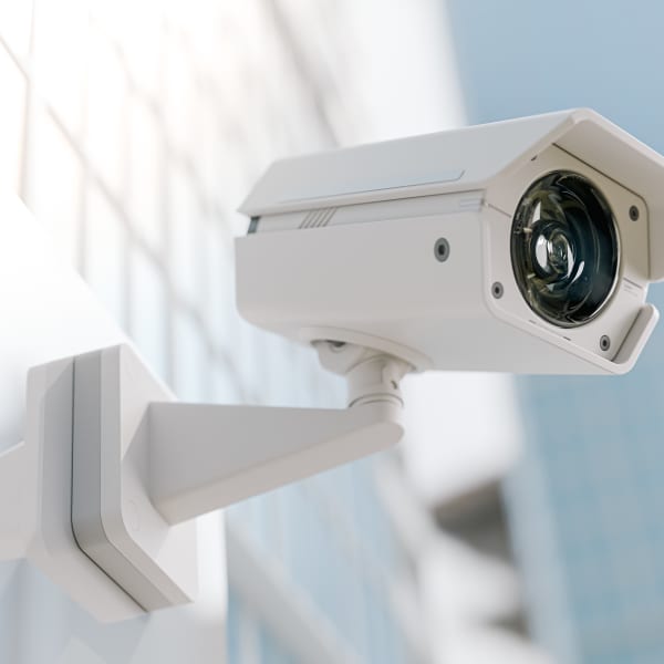 Weiße Überwachungskamera an der Fassade eines Gebäudes