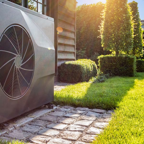 Wärmepumpen im Sonnenschein vor einem Einfamilienhaus.