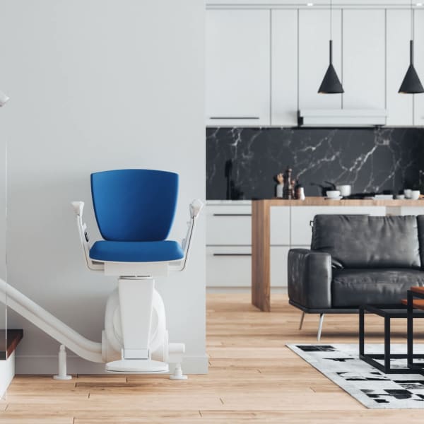 Sitzlift mit blauem Polster am Fußt einer Treppe in einem modernen Eigenheim