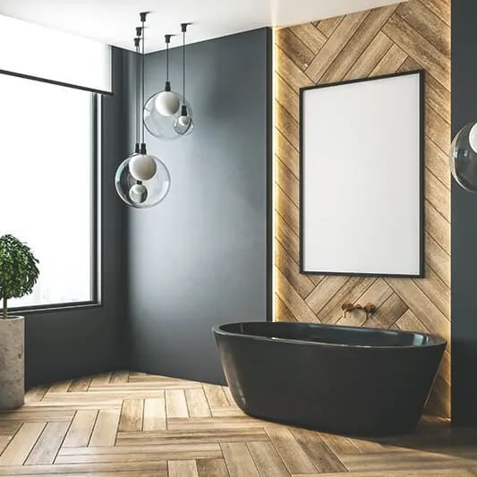Zu sehen ist ein modernes Badezimmer mit hellem Holzboden, dunkler Wand und dunklen Amarturen und Badewanne.