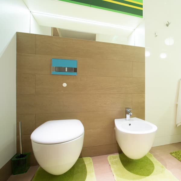 Modernes Bad mit wandhängender Toilette, Bidet und großem Waschtisch mit Unterbauschrank in grün und gelb