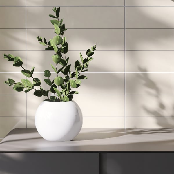 Matt schwarzer freistehender Waschtisch mit schwarzen Armaturen an der Wand darüber, daneben Zweige mit grünen Blättern in einer weißen Vase