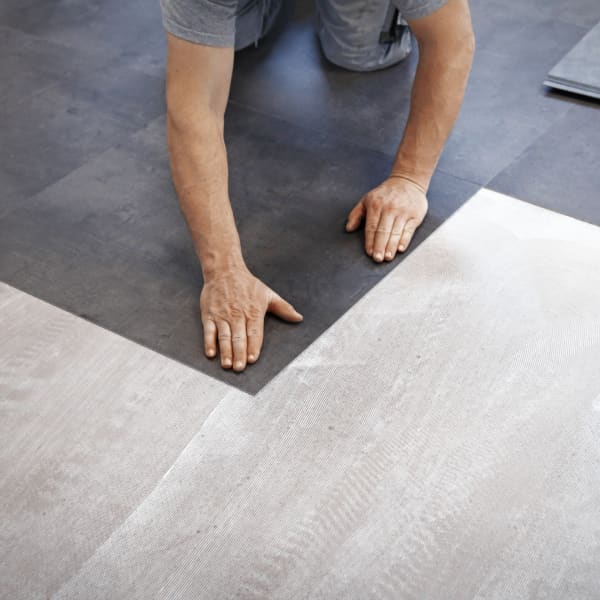 Dunkler Vinylboden wird vom Handwerker verlegt.