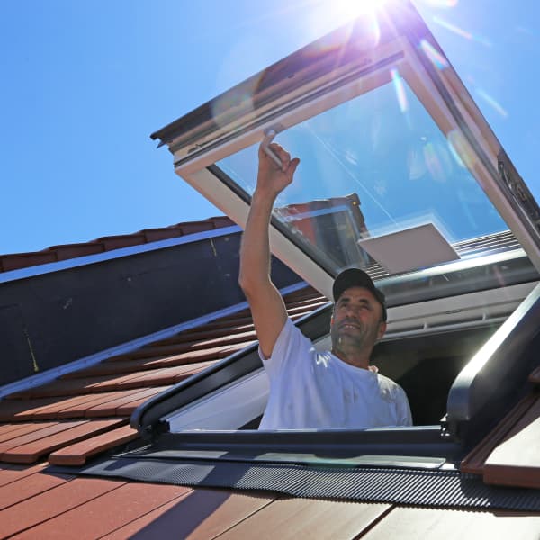 Monteur öffnet ein Dachlukenfenster.