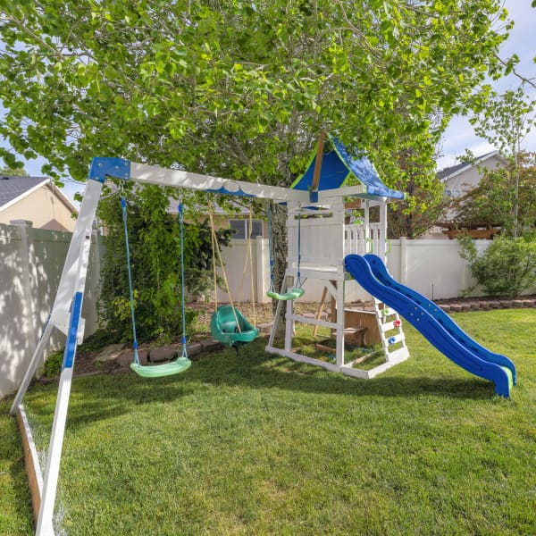 Garten mit einem Spielturm mit Rutsche und Schaukel.