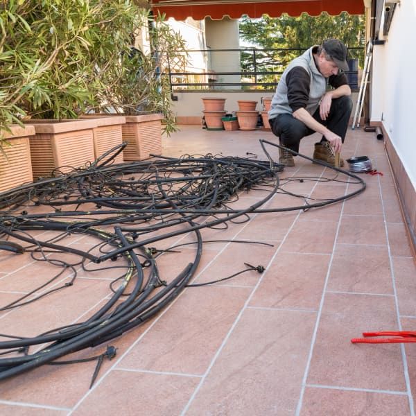 Mann installiert eine Gartenbewässerung mit schwarzen Schläuchen.